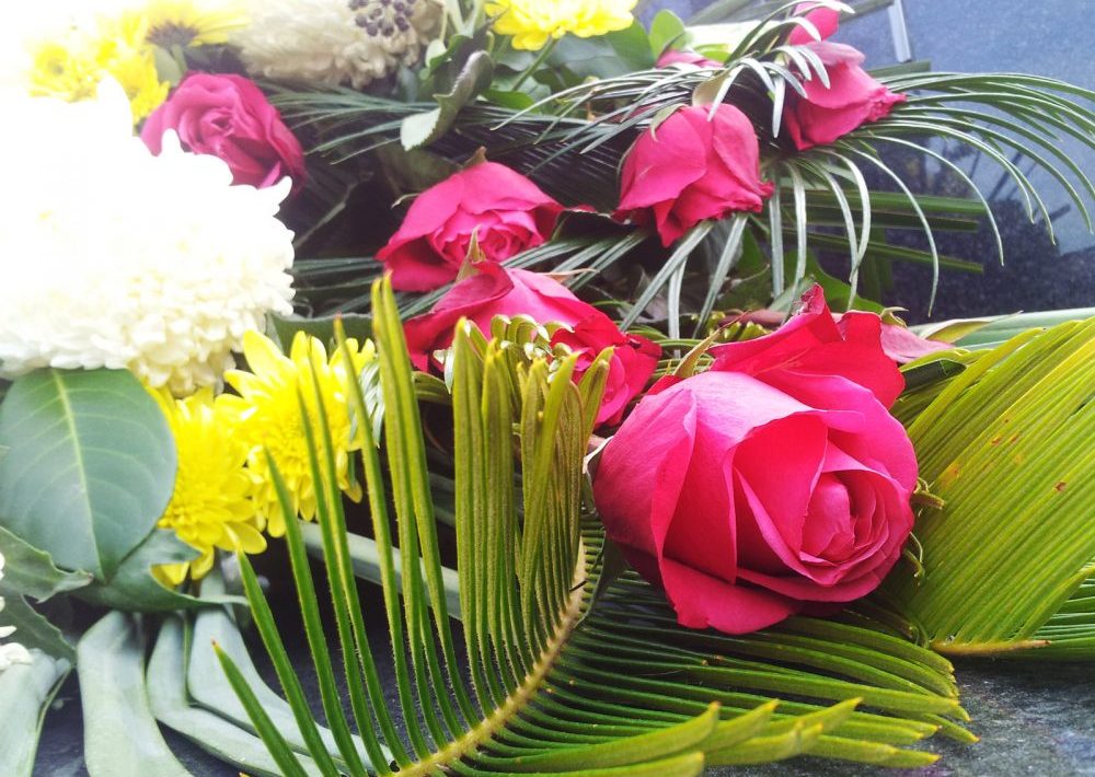 Mourning flower arrangement with red roses and white and yellow chrysanthemums