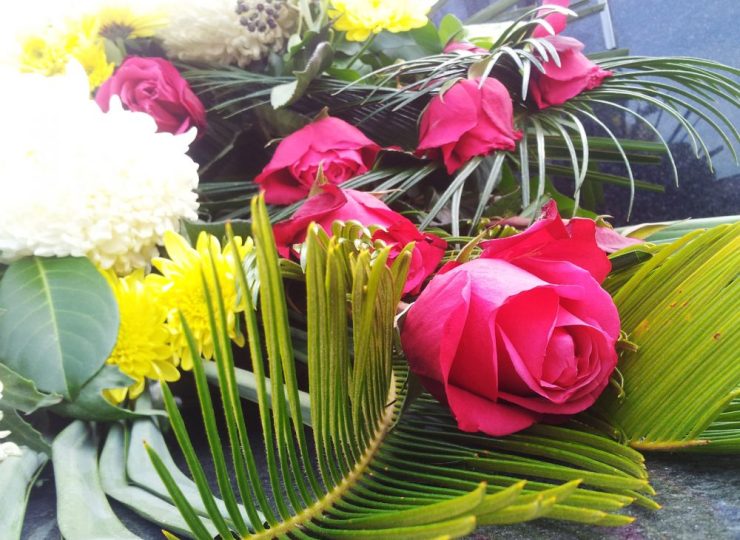 Mourning flower arrangement with red roses and white and yellow chrysanthemums