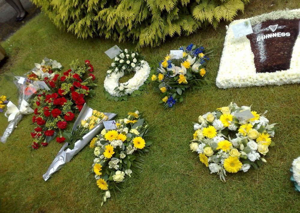Funeral wreaths and colourful flower arrangements displayed on grass