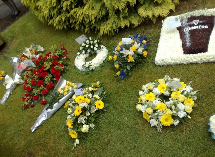 Funeral wreaths and colourful flower arrangements displayed on grass