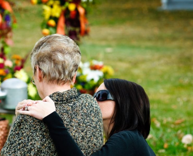 Una donna che abbraccia e consola una persona in lutto in un cimitero