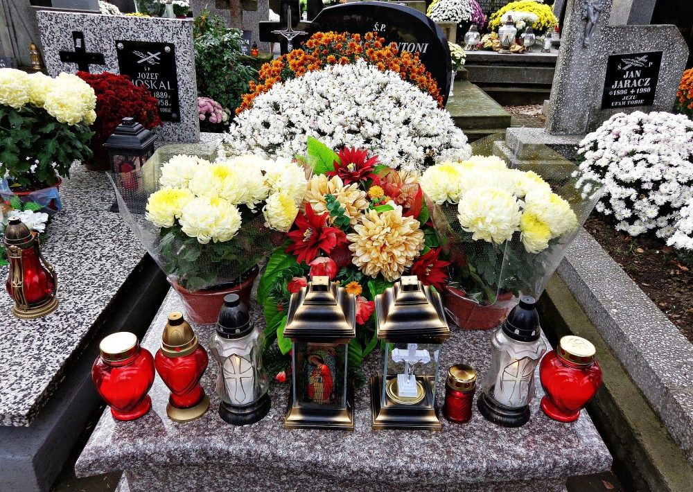 Grave decorated with flowers, funeral wreaths and memorial candles