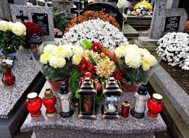 Grave decorated with flowers, funeral wreaths and memorial candles