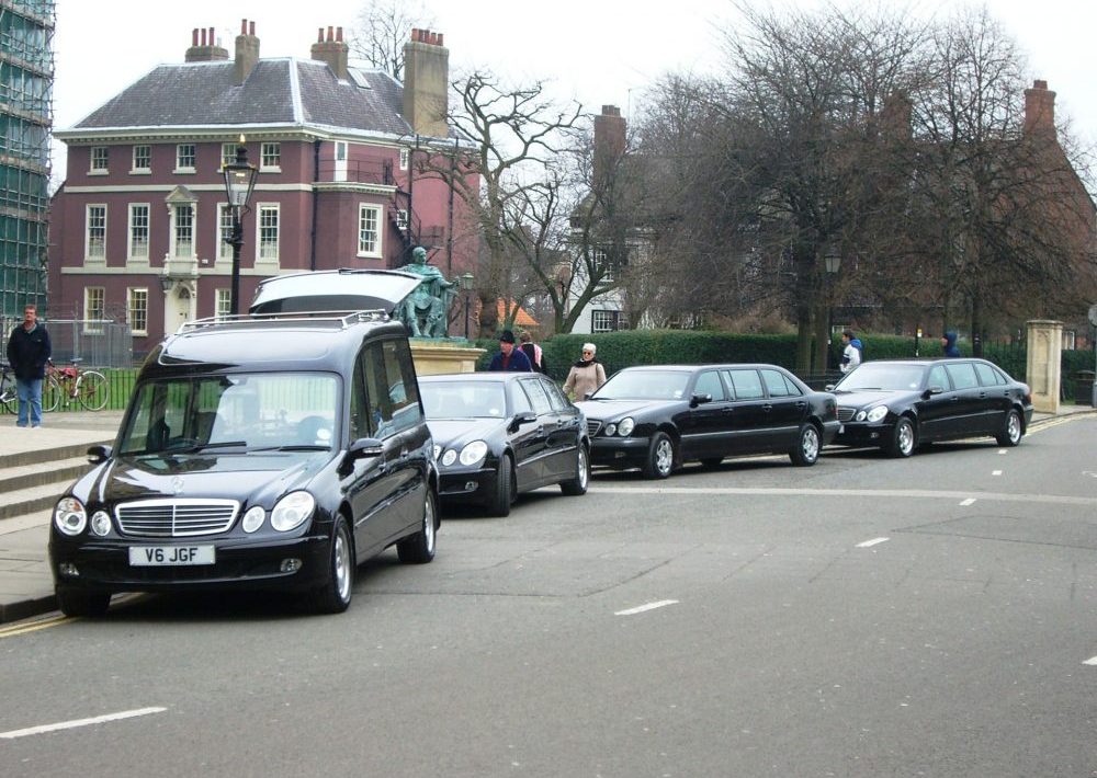 Funeral procession with a hearse followed by several black vehicles