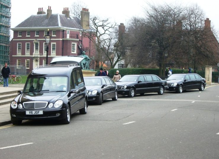 Funeral procession with a hearse followed by several black vehicles