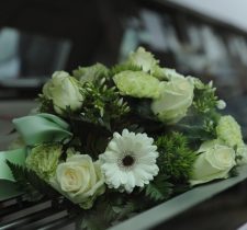 Composizione di rose bianche e gerbere su un'auto funebre – Agenzia funebre Haron